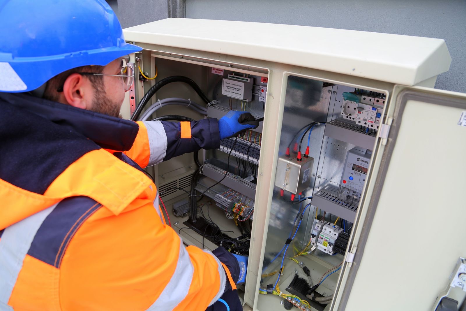 Electrician in hi-vis gear working on an electrical panel
